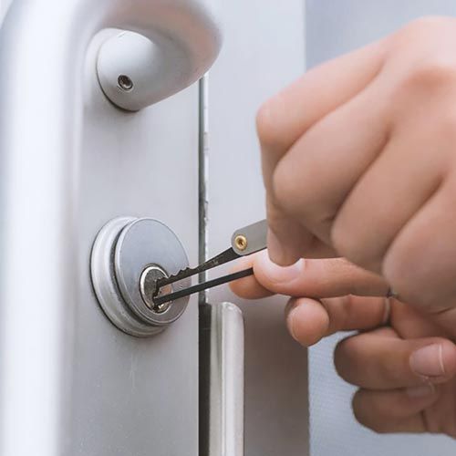 A Locksmith Using A Set Of Lock Picks To Unlock A Pulling Commercial Lock.