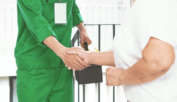 a man in a green uniform is shaking hands with a man in a white shirt .