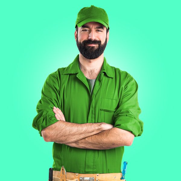 A Technician With A Beard Is Wearing A Green Uniform And A Green Hat.