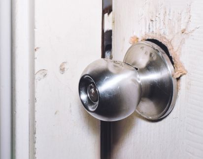 A Close Up Of A Broken Door Knob On A White Door.