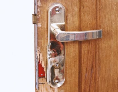 A Damage Wooden Door With A Metal Handle On It.
