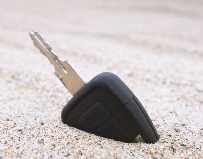 A Car Key Is Laying In The Sand On The Ground.