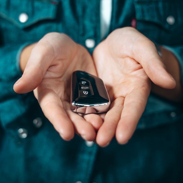 A Car Locksmith Is Holding A Remote Key Fob With Both Hands.