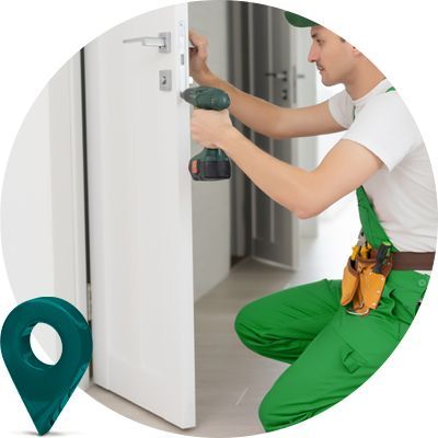A Locksmith Technician In Green Overalls Is Working On A door With A Drill.