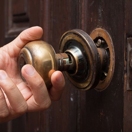 Expert Locksmith Disassembles A Damaged Doorknob Lock On A House Door.