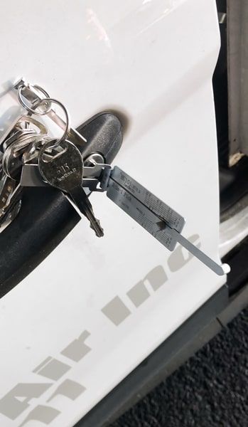 A White Car Door With A Key And Lock-Picking Tool.