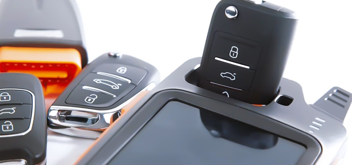 A Car Key Programmer With A Flip Key Inside And Others Around.