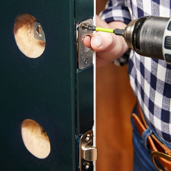 A House Locksmith Is Working On A Deadbolt Lock Installation On A Green Door.