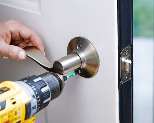 A Locksmith Is Installing A Lever Lock On The Front Door Of A House.