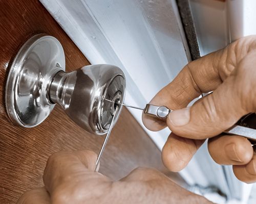 A Technician Is Using A Set Of Lock Picks To Unlock A Silver Doorknob.