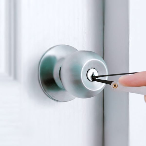 A Locksmith Is Using A Set Of Lock Picks To Unlock A Doorknob.