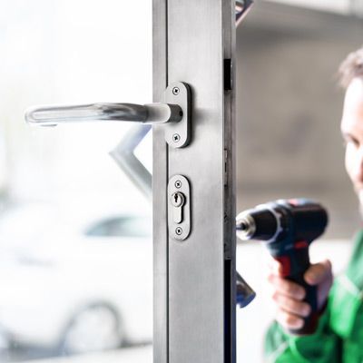 A Professional Locksmith Installs A New Lock On A Business.