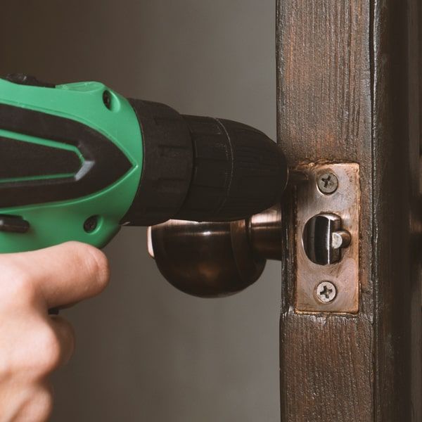 Installation Of A Lock On The Door Of A House.