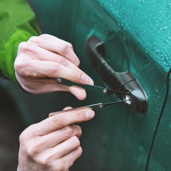 An Automotive Locksmith Is Unlocking A Car Door Lock With A Set Of Picks.