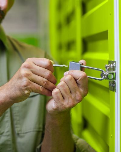 A Technician Uses A Lock Pick To Open A Storage Unit.