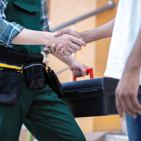 A Locksmith Technician In Green Overalls Is Shaking Hands With A Customer.