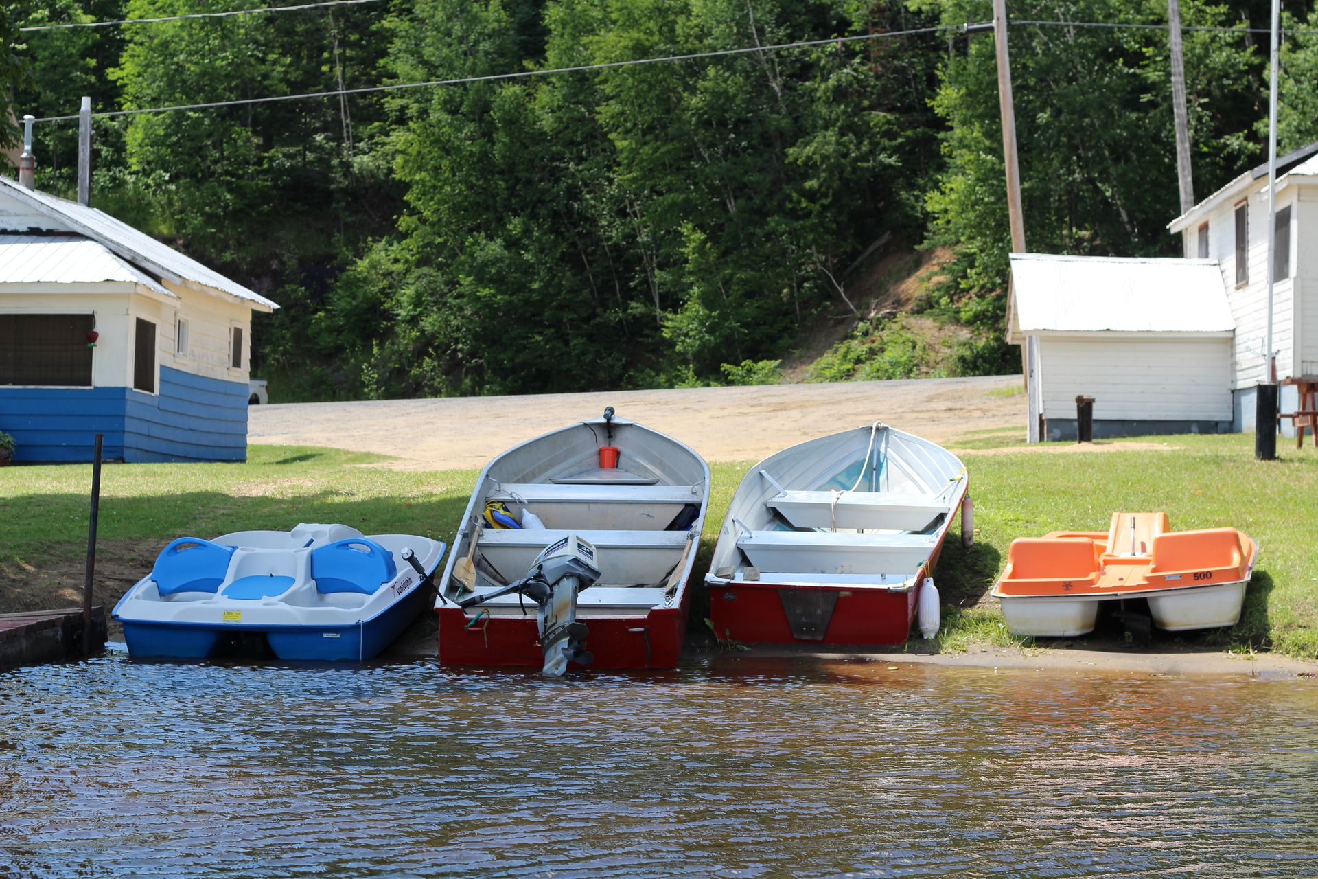 A row of boats are parked on the shore of a lake