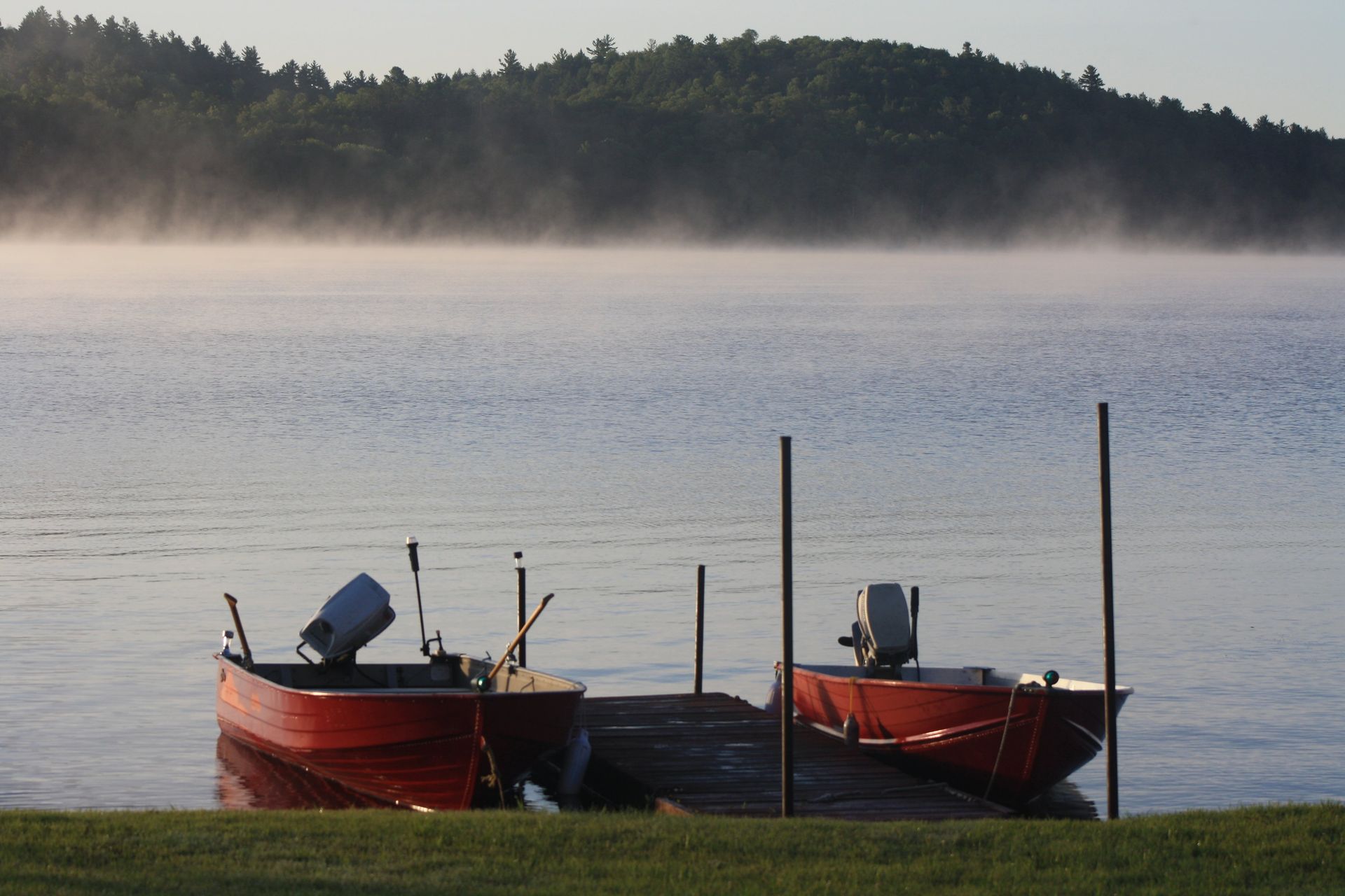 Two boats are docked at a dock on a foggy day