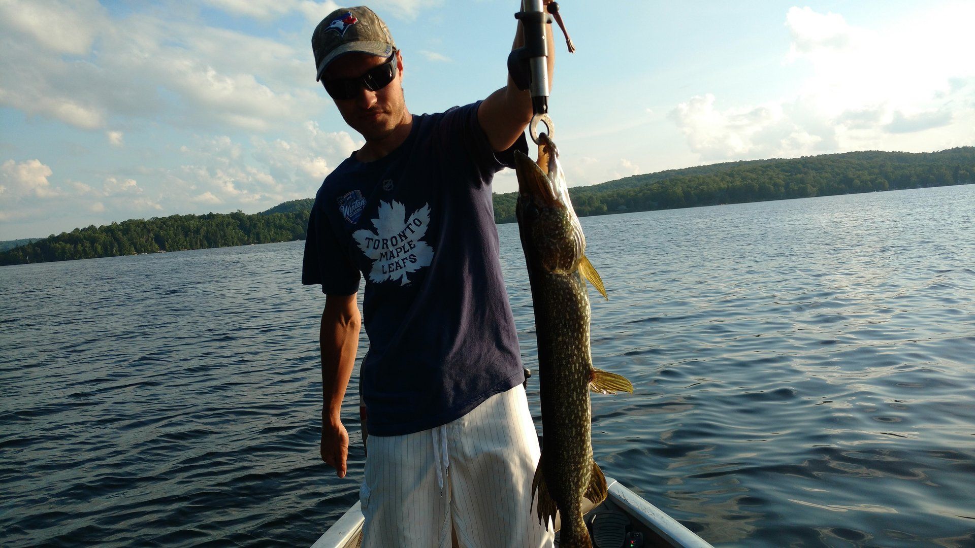 A man is standing in a boat holding a large fish.