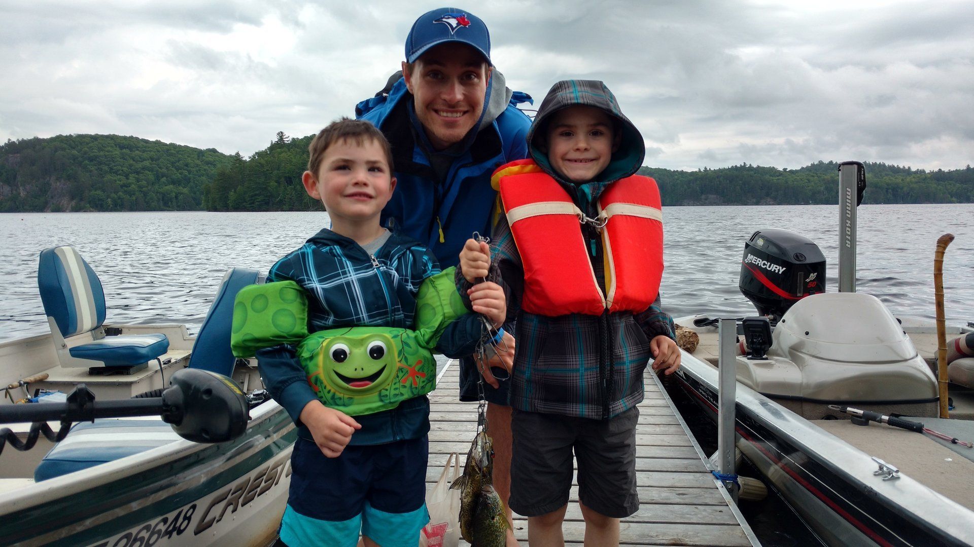 A man and two children are standing on a dock next to a boat.