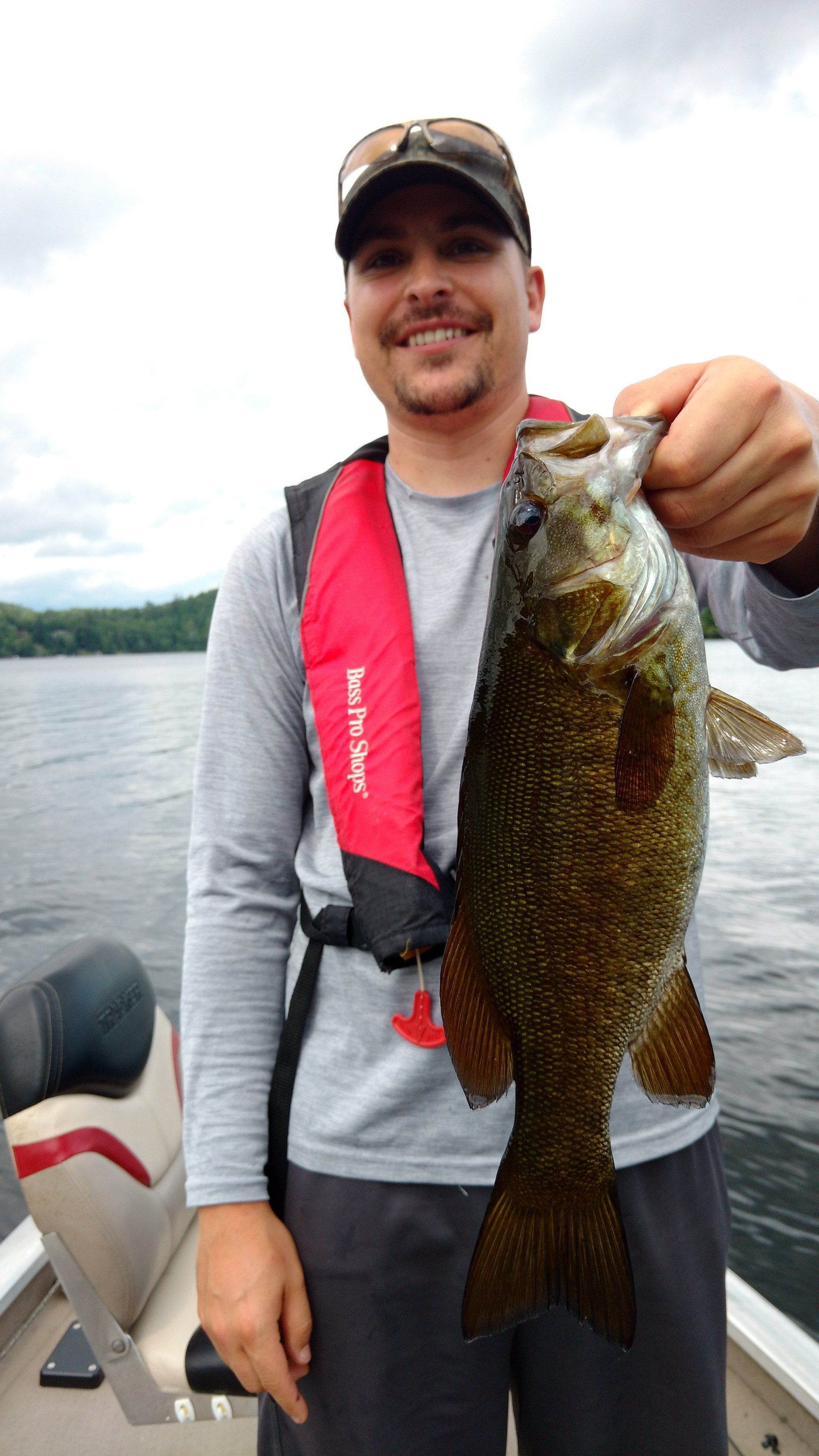 A man is holding a large fish in his hands while standing on a boat.