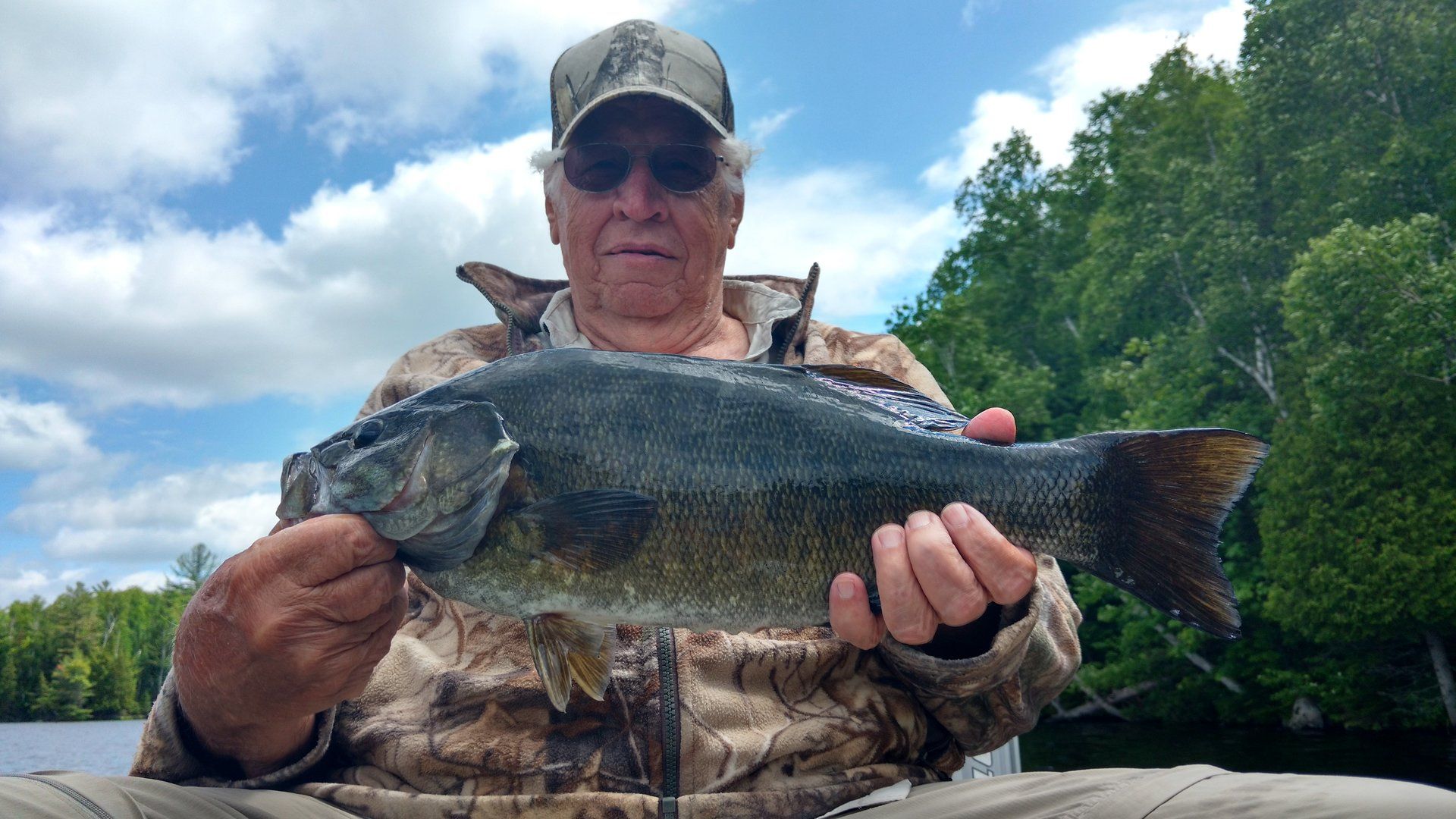 A man is holding a large bass in his hands.