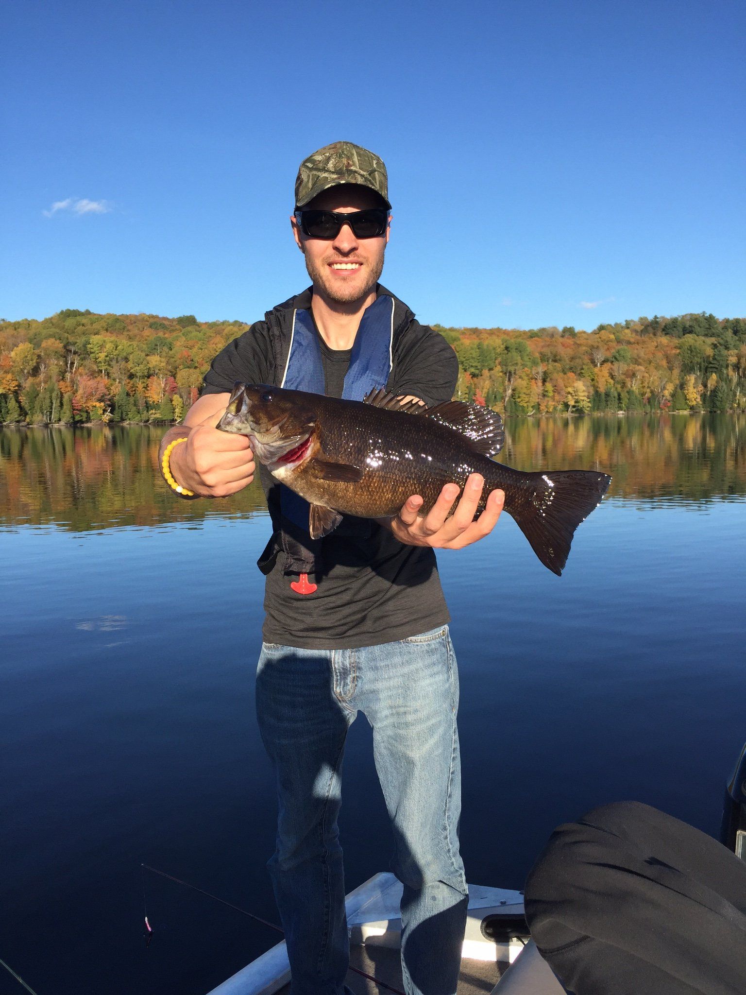 A man is standing on a boat holding a large fish.