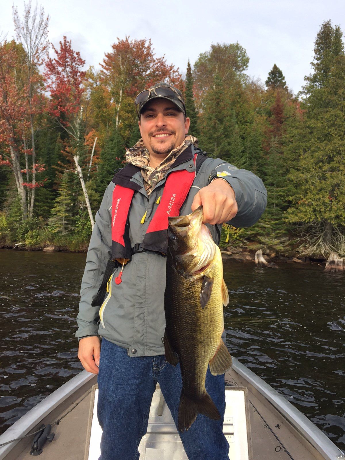 A man in a boat is holding a large fish in his hand.