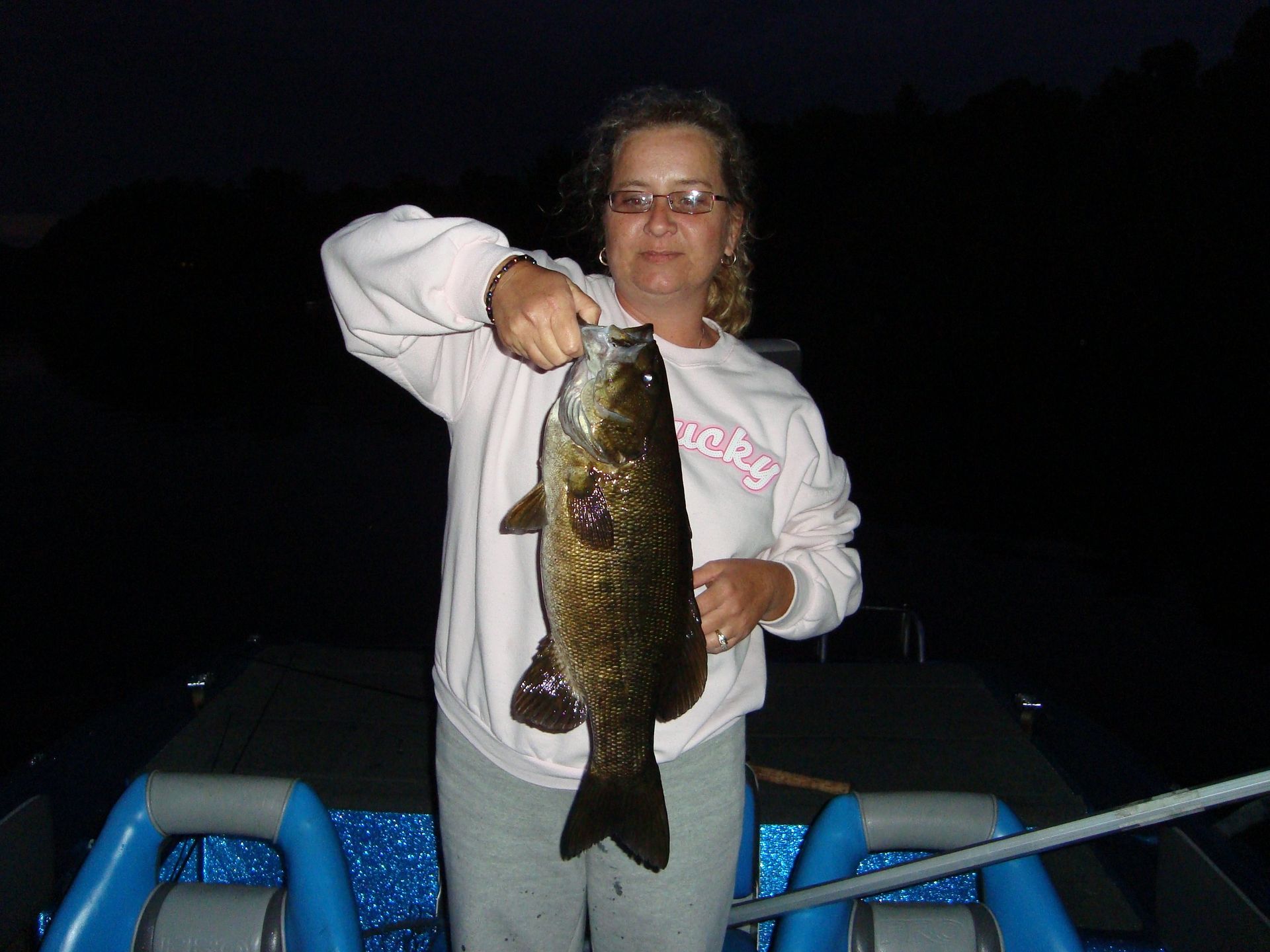 A woman in a pink sweater is holding a large fish