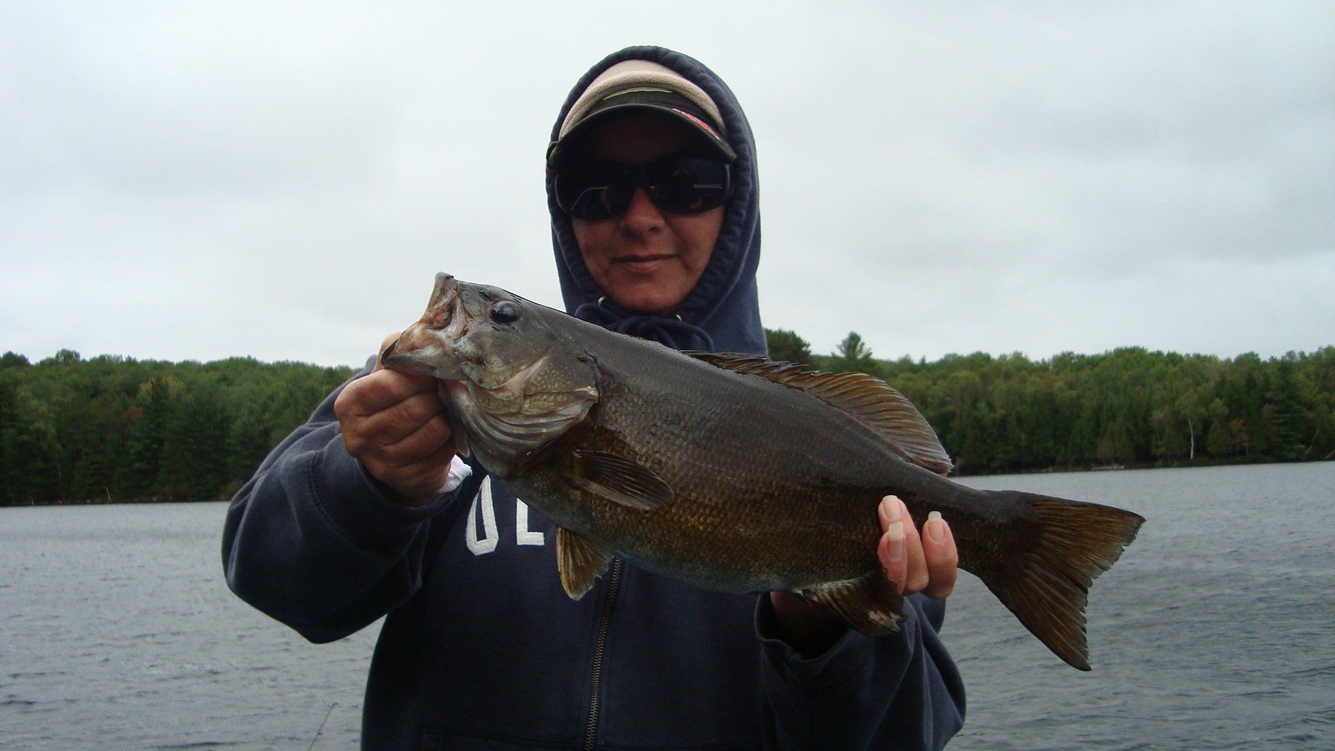 A man in a hoodie is holding a large fish