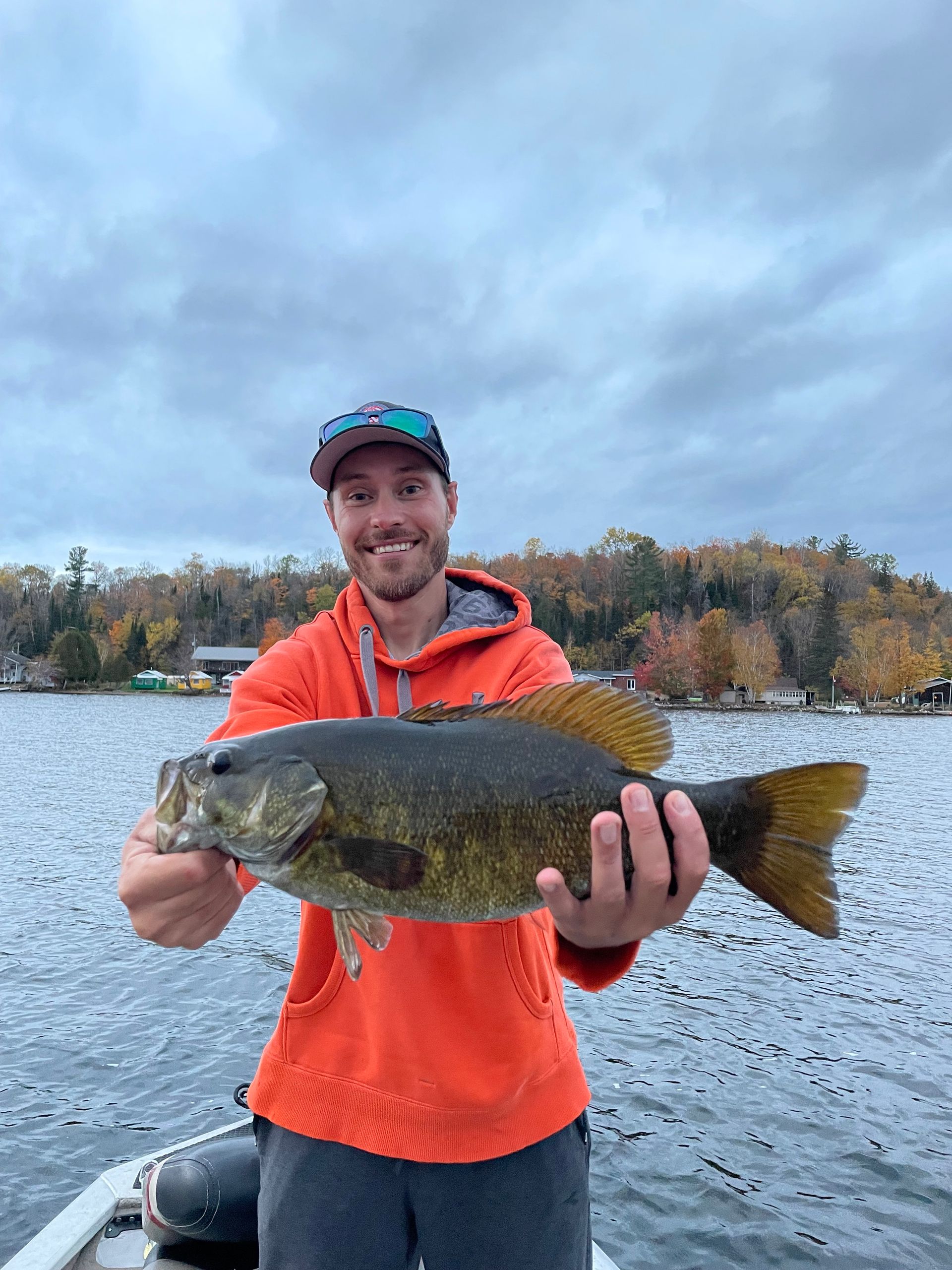 A man is holding a large fish in his hands while standing on a boat.