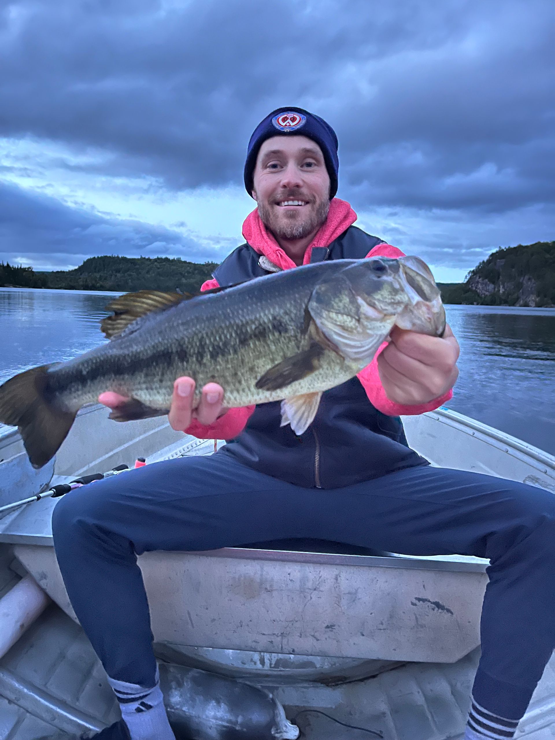 A man is sitting in a boat holding a large fish.