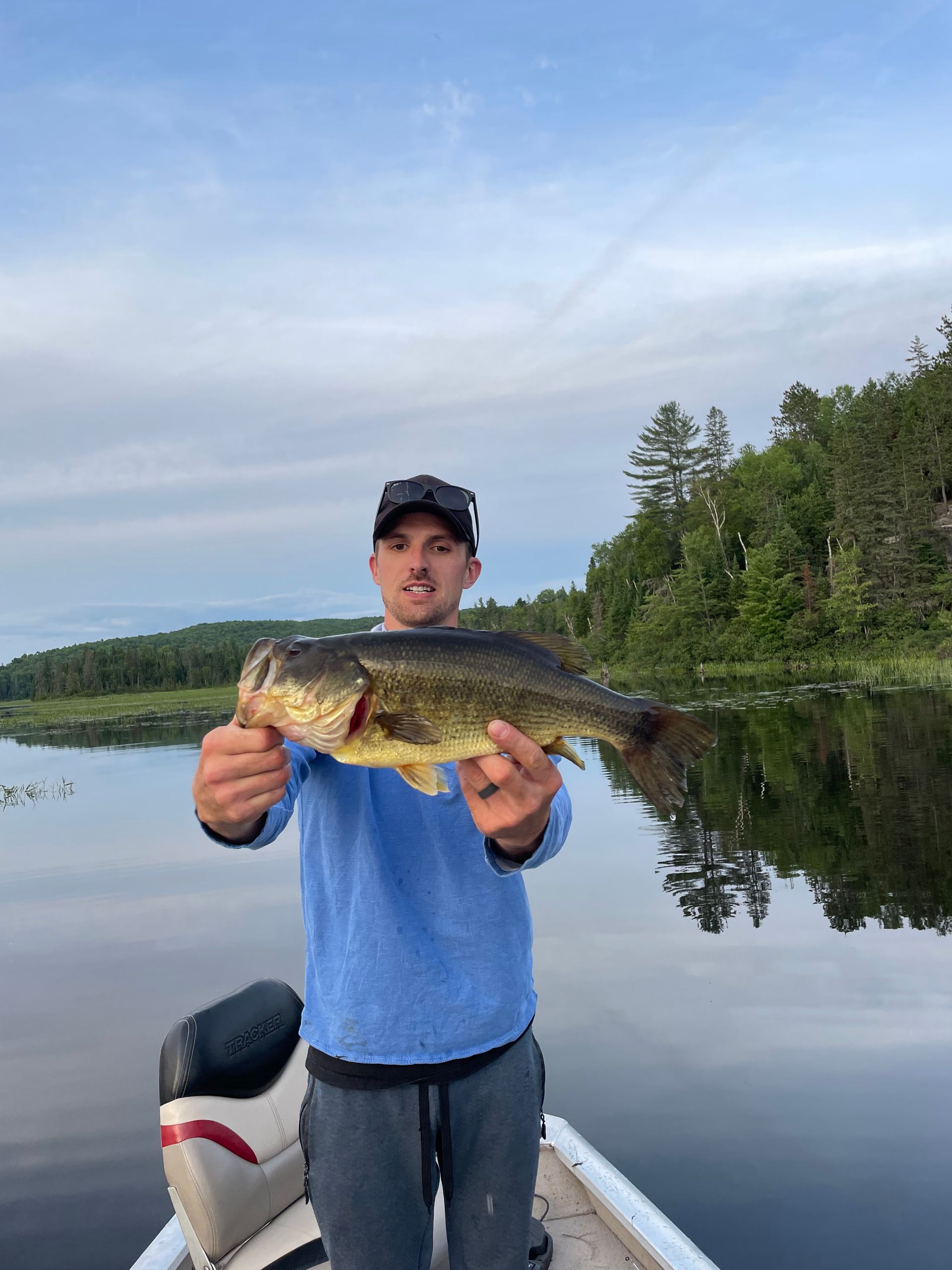 A man in a boat is holding a large fish in his hands.