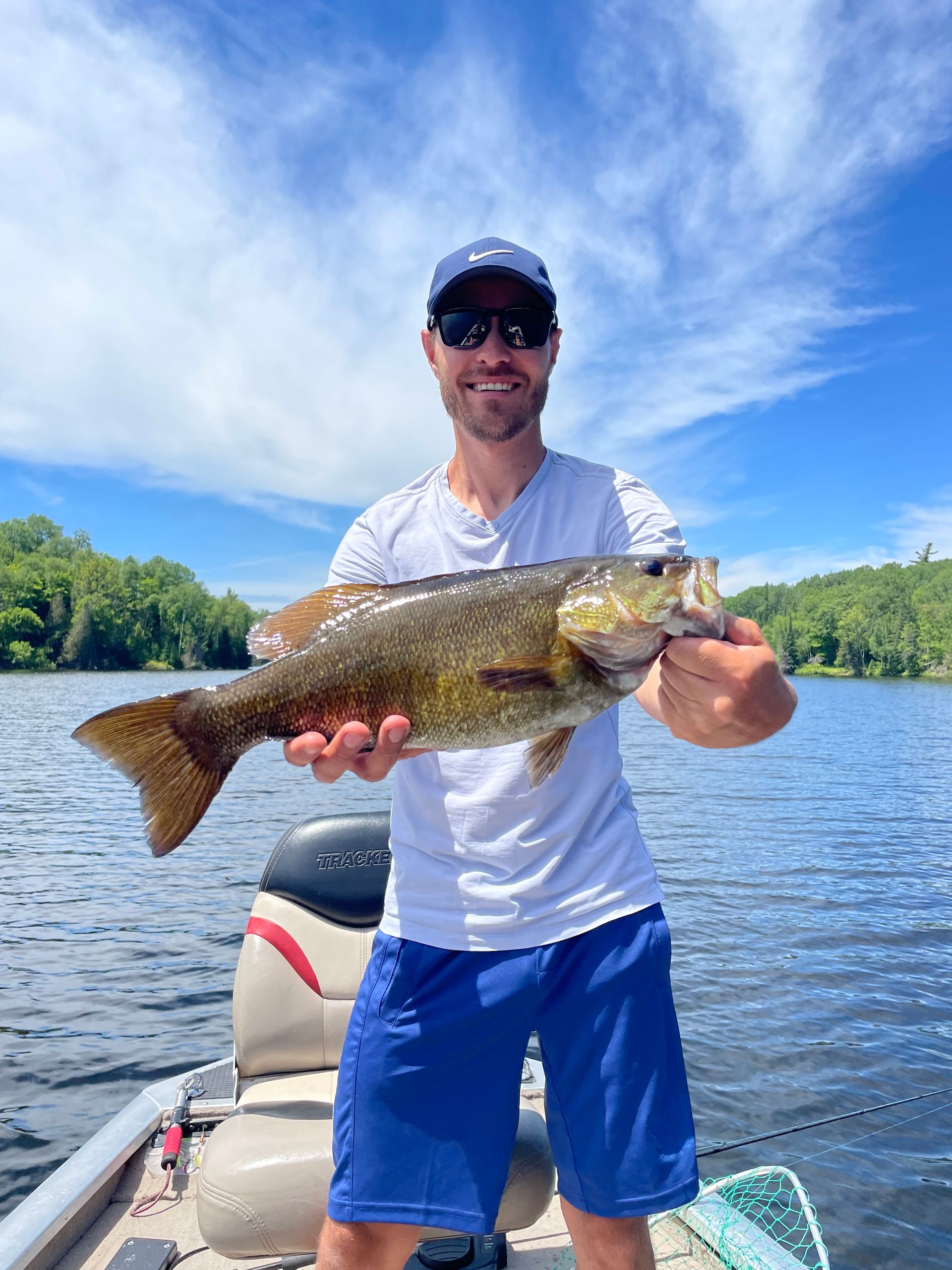 A man is standing on a boat holding a large fish.