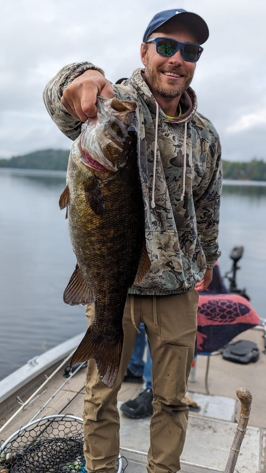 A man is holding a large fish on a boat.