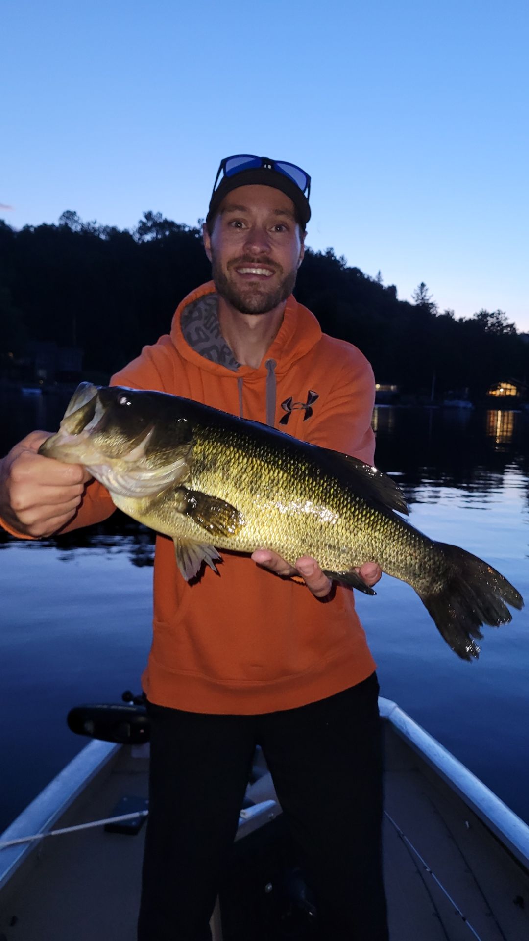 A man is holding a large fish in his hands while standing on a boat.