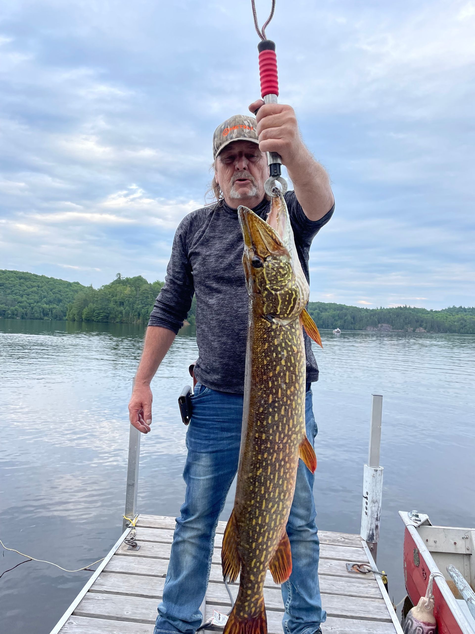 A man is standing on a dock holding a large fish.