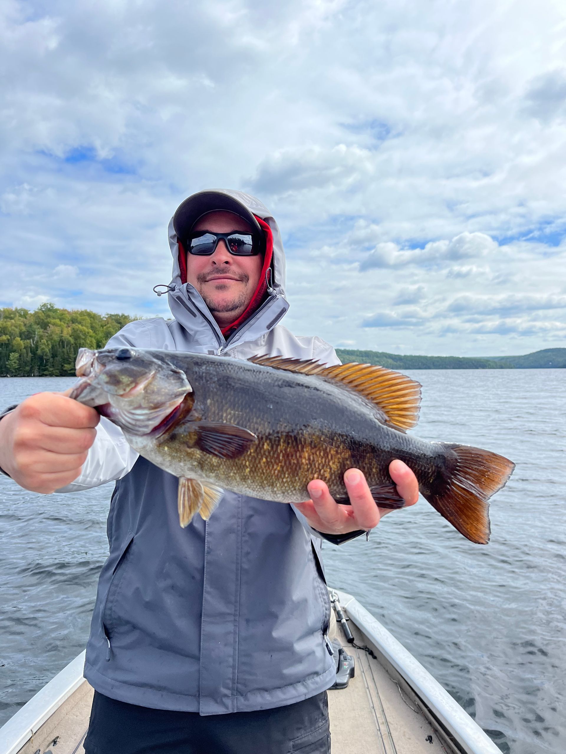 A man is holding a large bass on a boat.