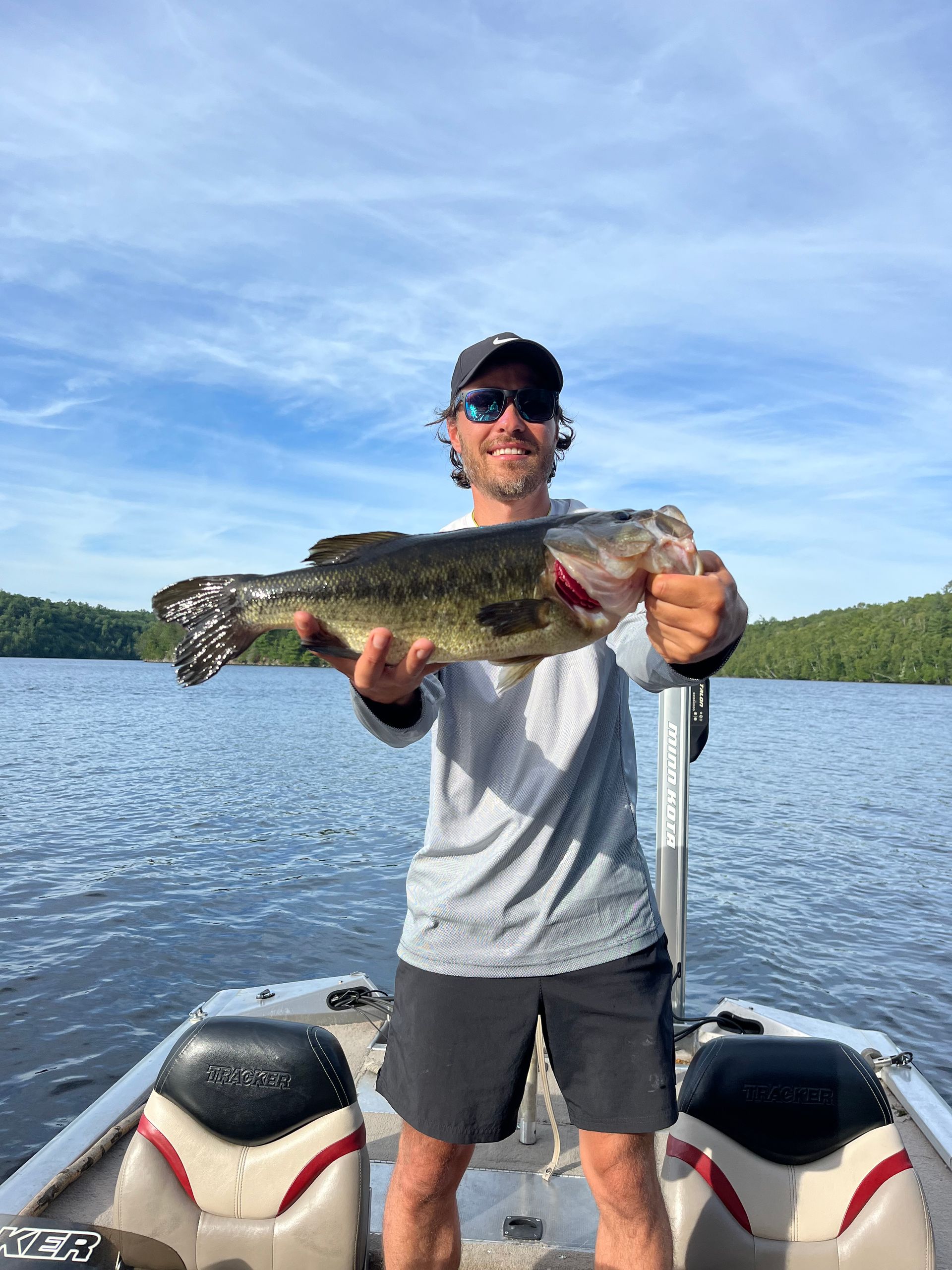 A man is standing on a boat holding a large fish.