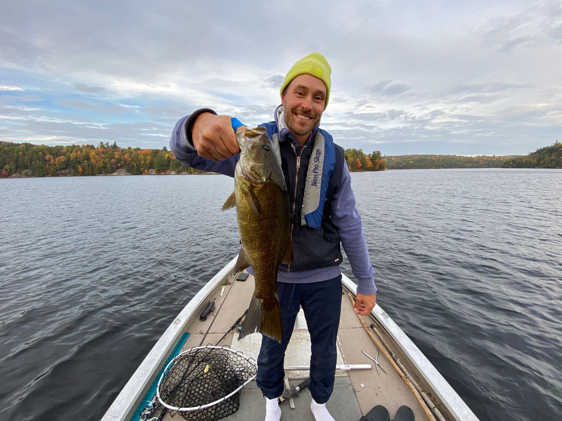 A man is standing on a boat holding a fish in his hand.