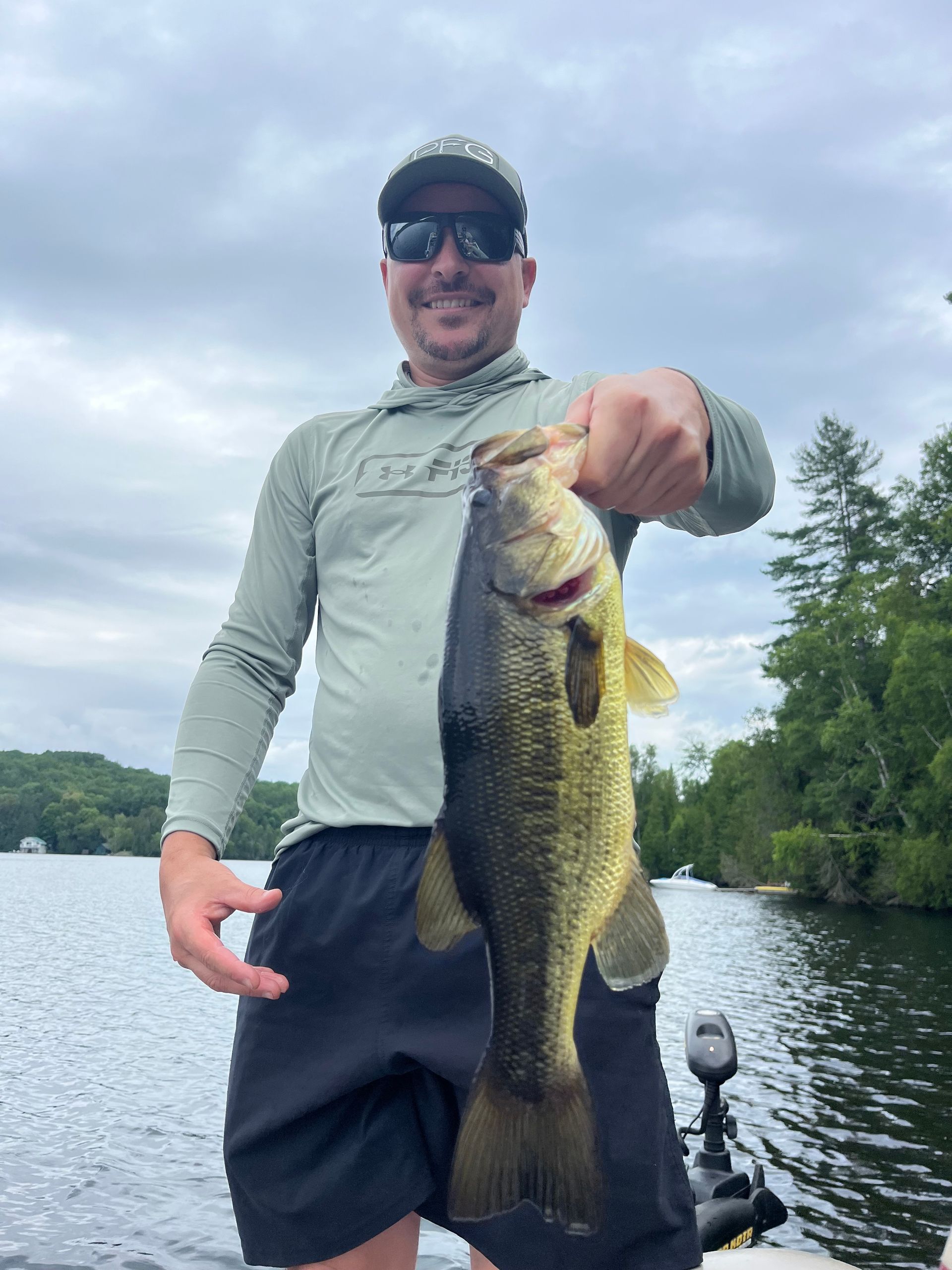 A man is standing on a boat holding a large fish.