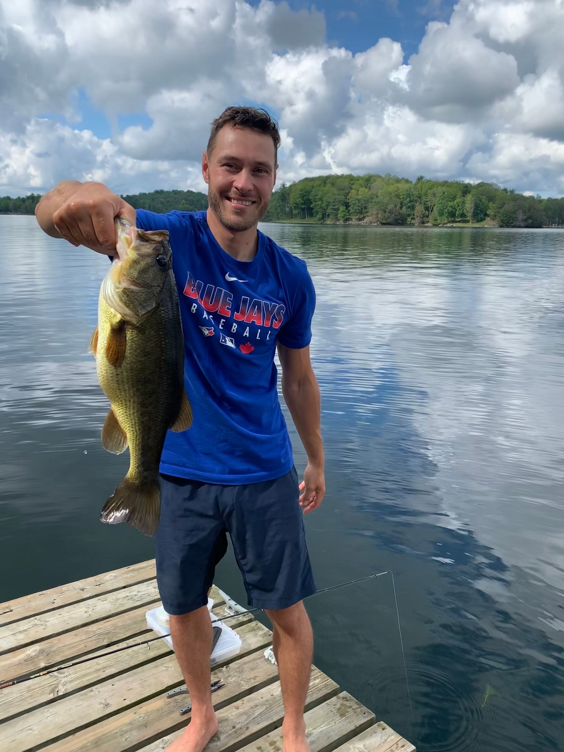 A man is standing on a dock holding a large fish.
