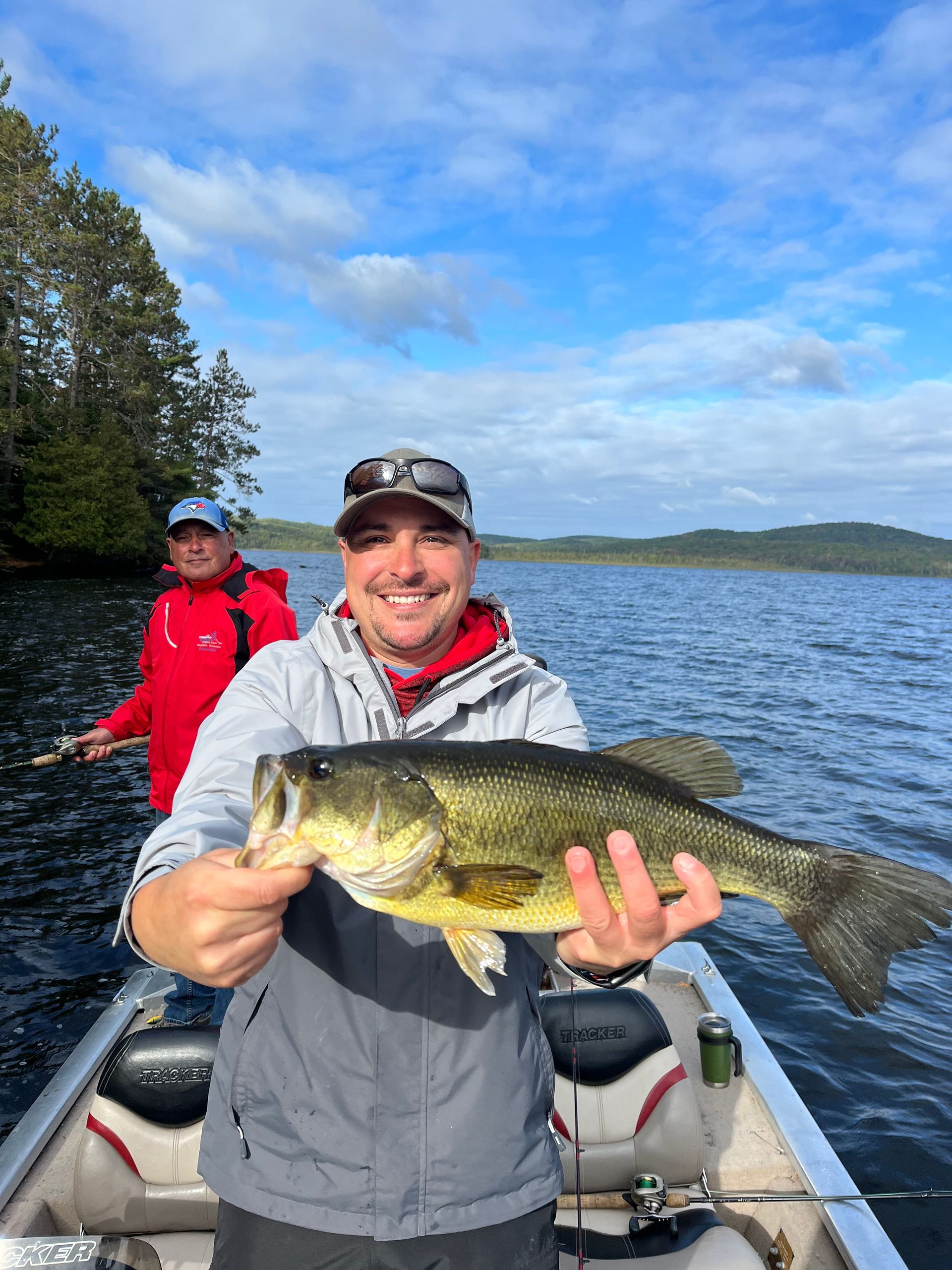 A man is holding a large bass on a boat.