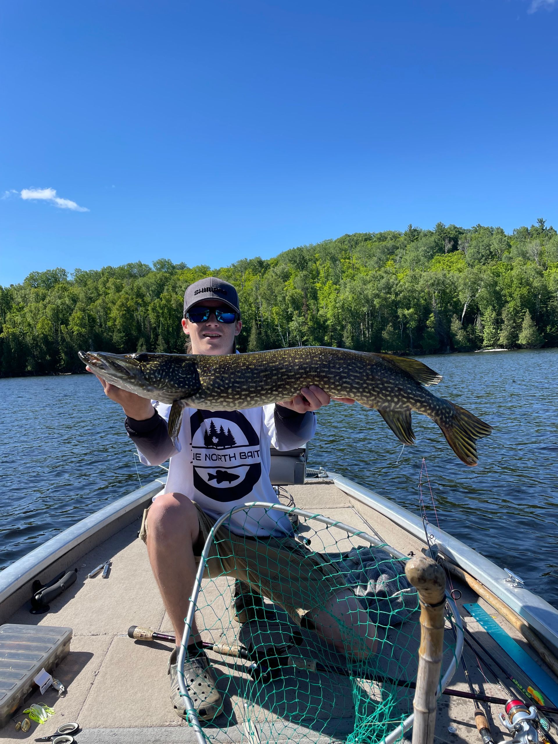 A man is sitting in a boat holding a large fish.