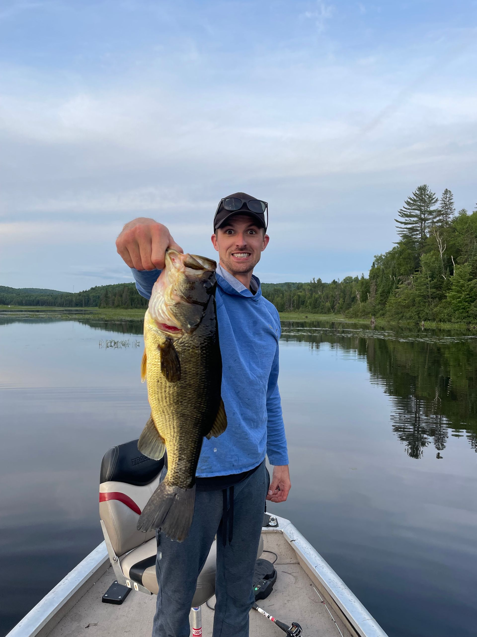 A man is standing on a boat holding a large fish.
