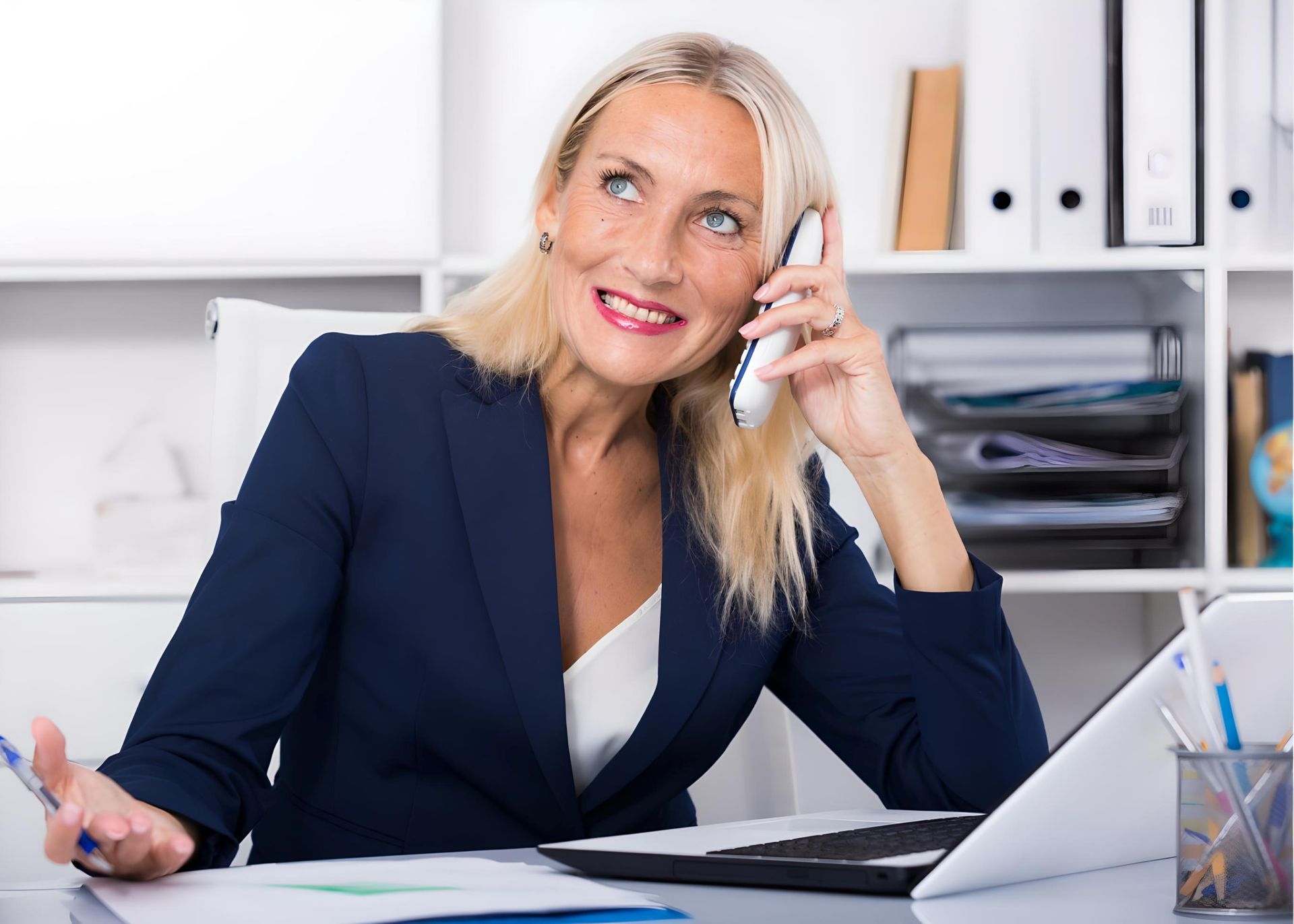 a woman is sitting at a desk talking on a cell phone