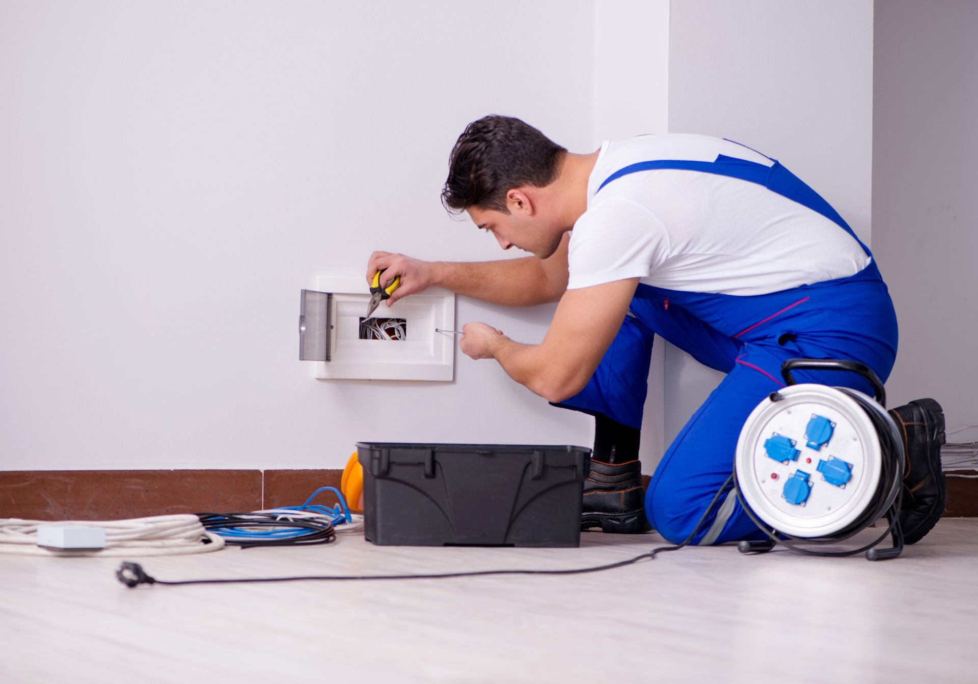 a man in blue overalls is working on an electrical box