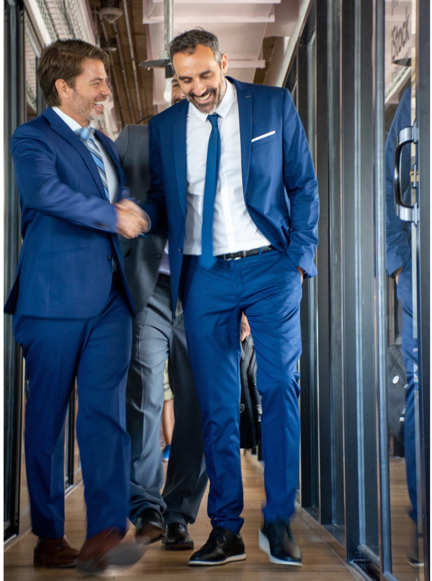 three men in suits and ties are walking down a hallway