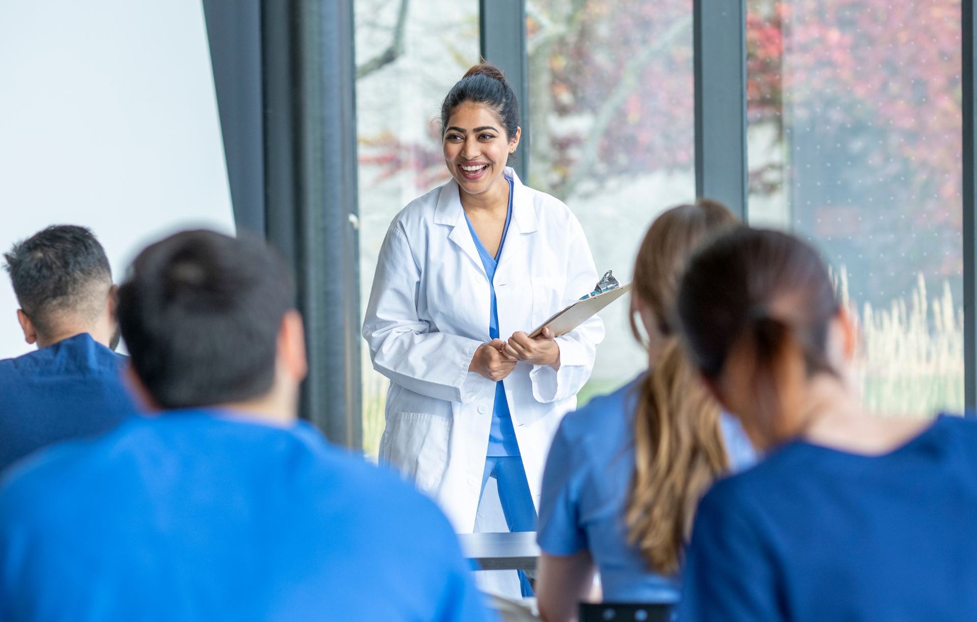 a female doctor is giving a presentation to a group of medical students .