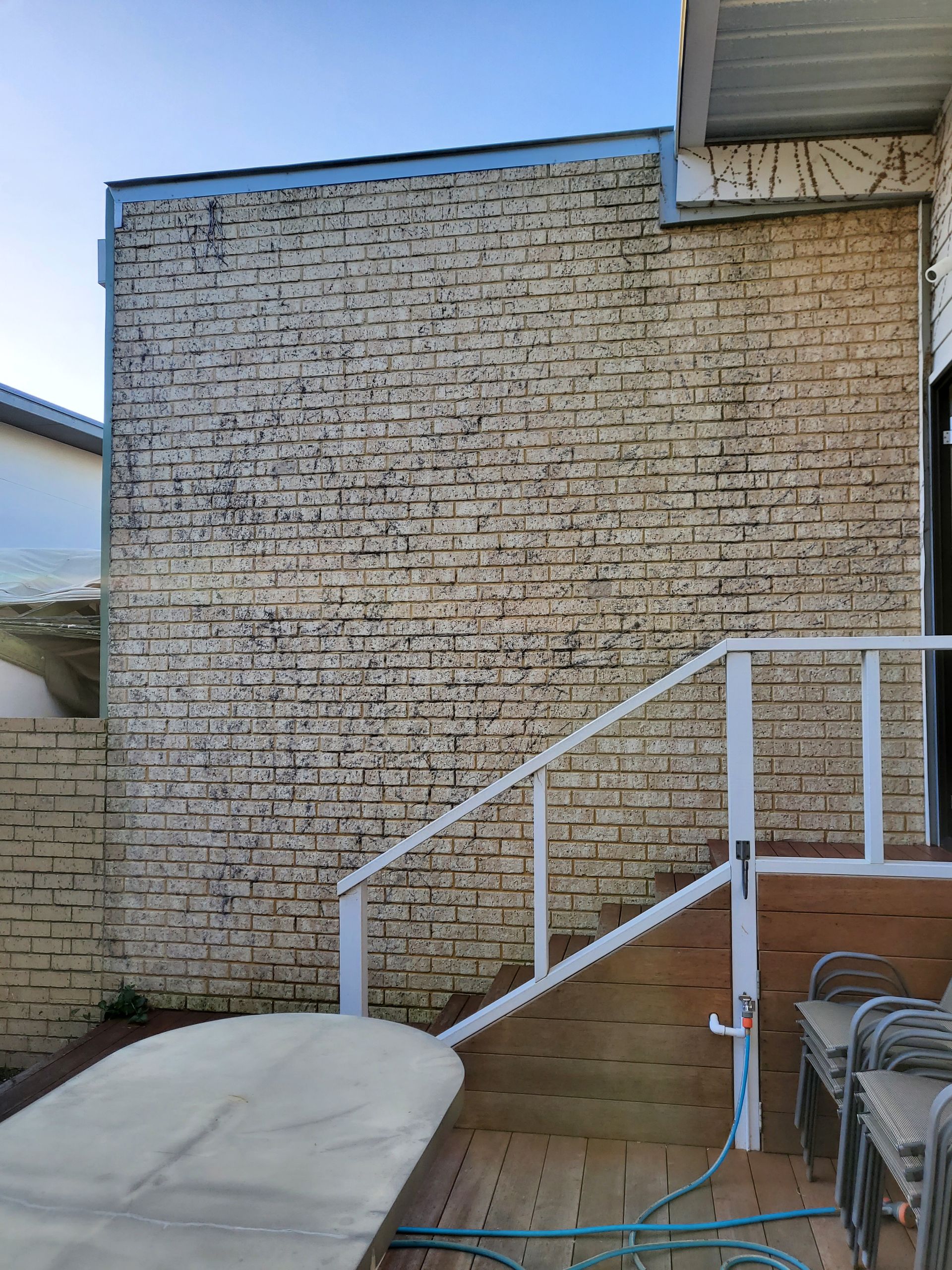 Stone facade of a building with a white railing and wooden deck.